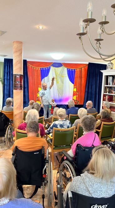 Marionettenspieler mit Puppe und Bewohner:innen